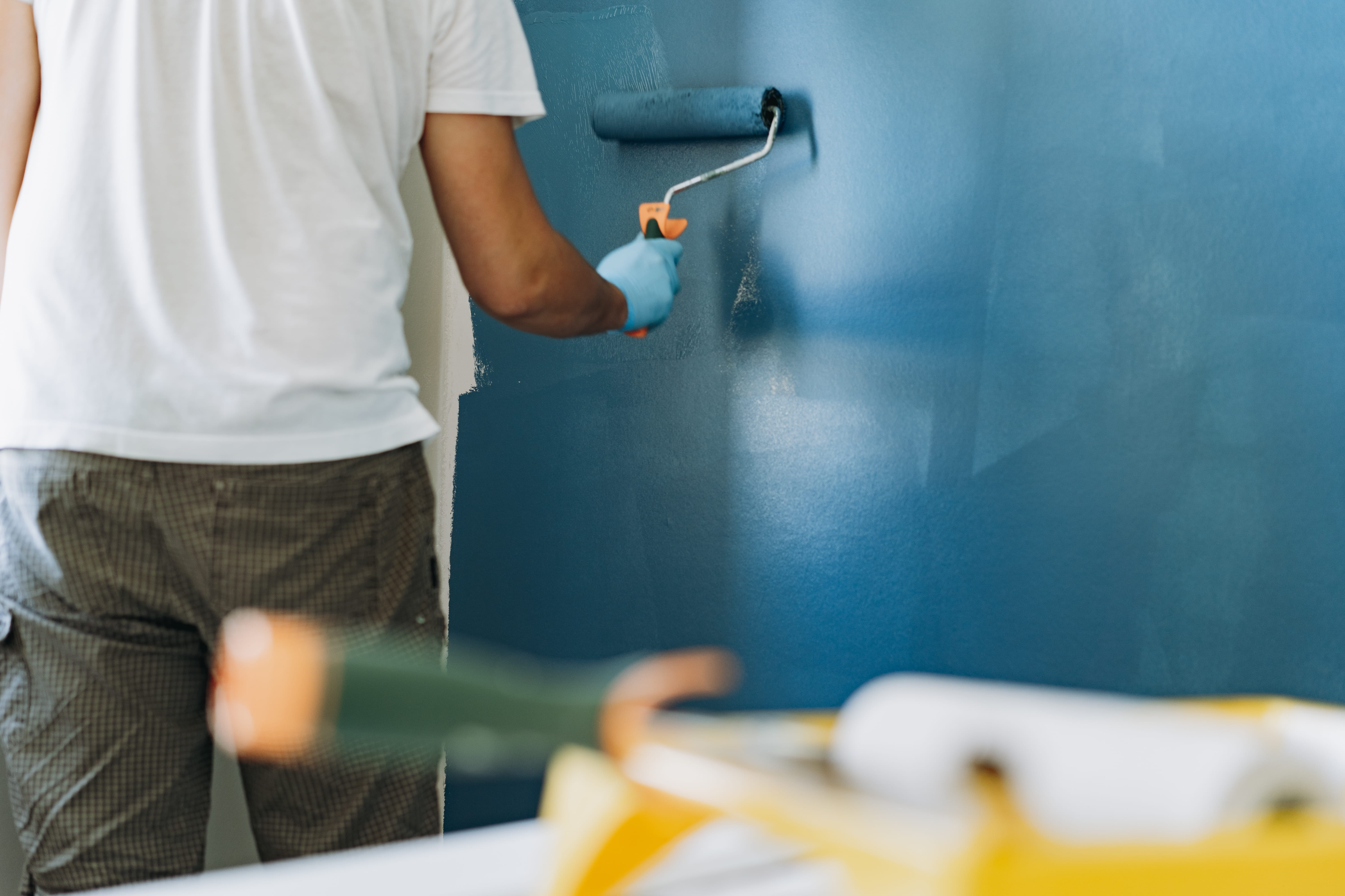 Interior wall being rolled with blue paint